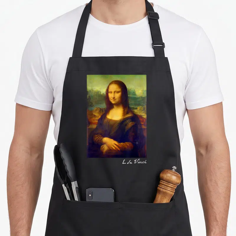 Leonardo famous aprons - Rectangular photo of a woman in a landscape with script text below the image to the right — shown on a black cotton canvas apron against a white background