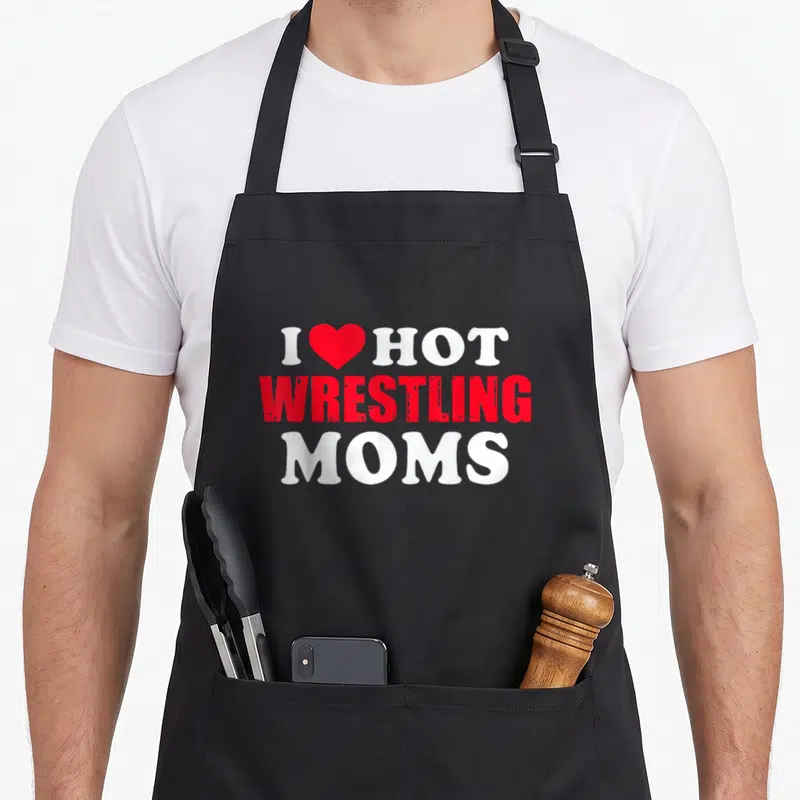 Hot wrestling apron - White and red text I red heart HOT WRESTLING MOMS on black — shown on a black cotton canvas apron against a white background