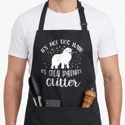 Glitter dog apron - White dog silhouette surrounded by stars with arched text reading It's Not Dog Hair Its Great — shown on a black cotton canvas apron against a white background
