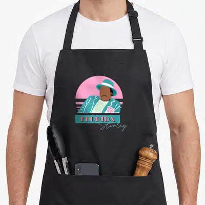 Stanley florida apron - Minimalist man in teal suit and hat against pink sun with FLORIDA text in blue rectangle — shown on a black cotton canvas apron against a white background
