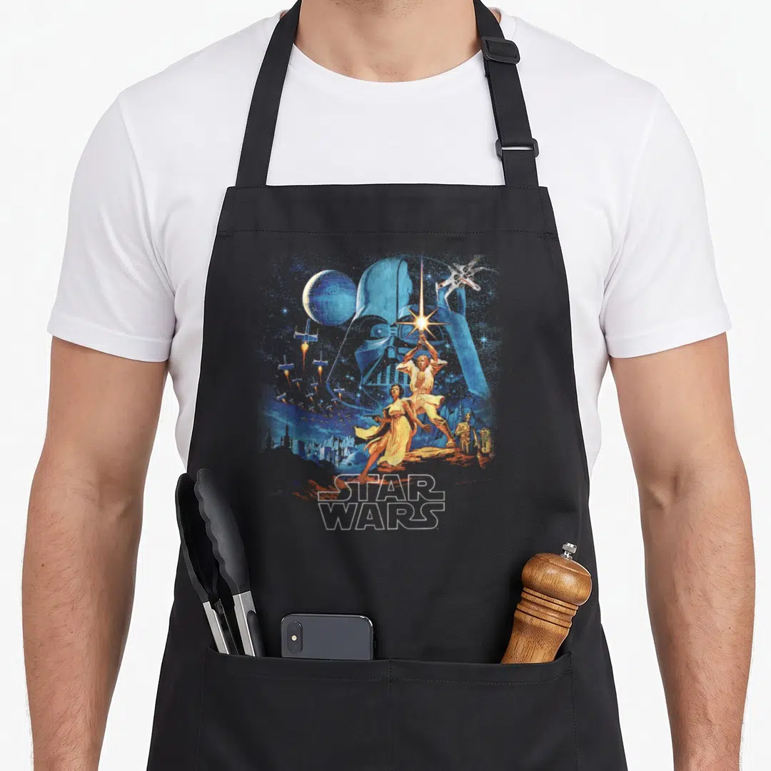 Faded hope apron - Vintage Star Wars poster art with Darth Vader helmet Luke Leia C-3PO ships and Death Star in blue — shown on a black cotton canvas apron against a white background