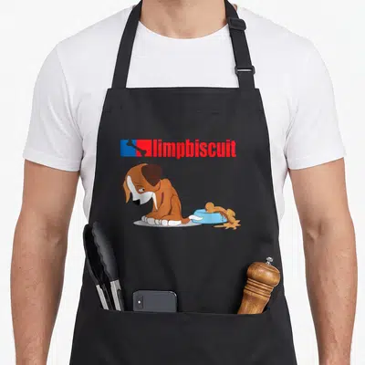 Limp biscuits apron - Sad cartoon dog next to blue bowl with bone and red limpbiscuit text — shown on a black cotton canvas apron against a white background