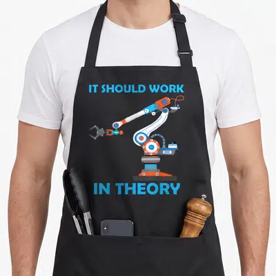 Robotic robot engineer apron - Robotic arm illustration with IT SHOULD WORK IN THEORY text — shown on a black cotton canvas apron against a white background