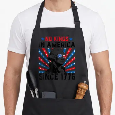 Distressed king apron - George Washington in sunglasses with No Kings In America Since 1776 text and starburst — shown on a black cotton canvas apron against a white background
