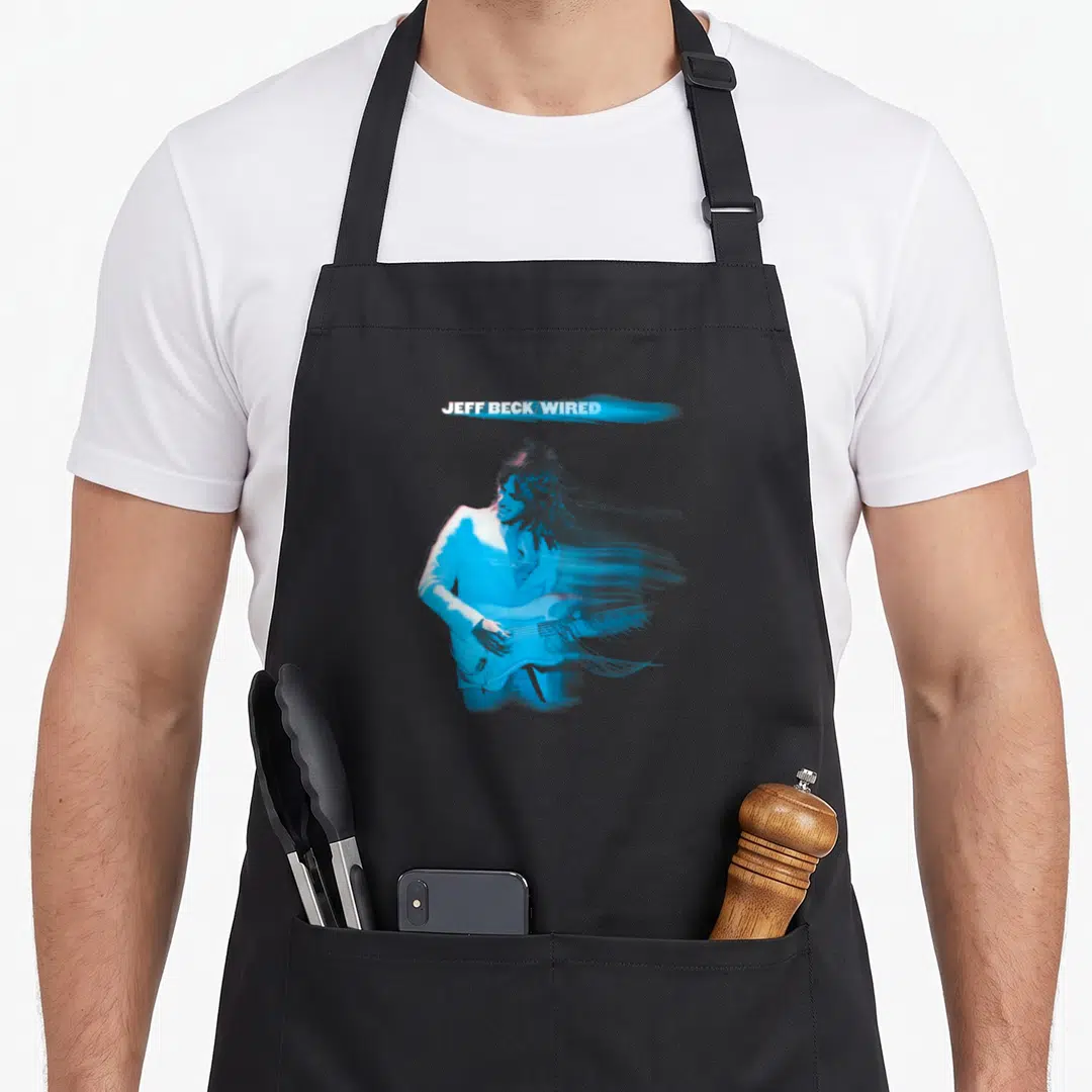 Jeff musician apron - JEFF BECK/WIRED text above blue motion-blurred man playing electric guitar — shown on a black cotton canvas apron against a white background