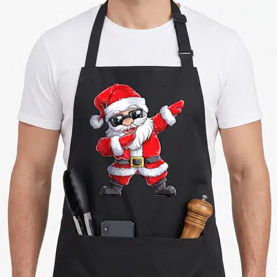 Dab santa claus apron - Cartoon Santa dabbing in red white black sunglasses — shown on a black cotton canvas apron against a white background