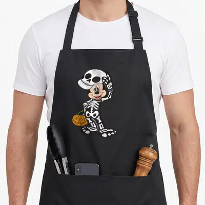 Funny costume skeleton apron - Cartoon mouse in black skeleton suit tipping white skull hat holding orange pumpkin — shown on a black cotton canvas apron against a white background