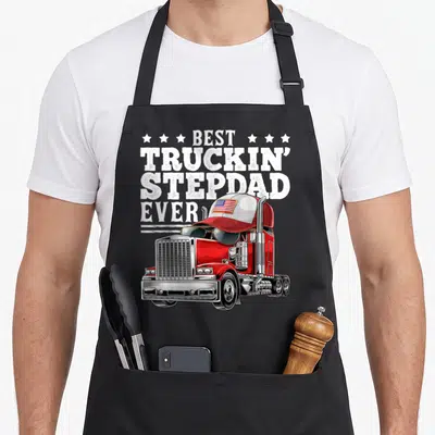 Truckin stepdad father day apron - Red semi-truck with flag cap and BEST TRUCKIN STEPDAD EVER text — shown on a black cotton canvas apron against a white background