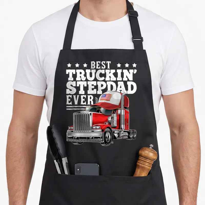 Truckin stepdad father day apron - Red semi-truck with flag cap and BEST TRUCKIN STEPDAD EVER text — shown on a black cotton canvas apron against a white background