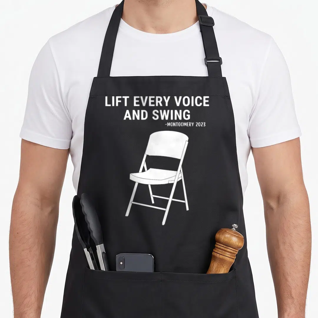 Lift chair apron - White folding chair illustration with stacked text LIFT EVERY VOICE AND SWING MONTGOMERY 2023 — shown on a black cotton canvas apron against a white background