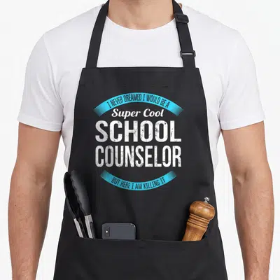Vintage school counselor apron - Stacked white distressed text reading Super Cool School Counselor between two blue — shown on a black cotton canvas apron against a white background