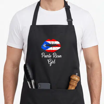 Lip pride apron - Lips filled with Puerto Rican flag pattern above white Puerto Rican Girl script text — shown on a black cotton canvas apron against a white background