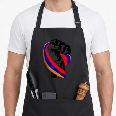Armenian pride apron - Black raised fist wrapped in orange blue and red ribbon — shown on a black cotton canvas apron against a white background