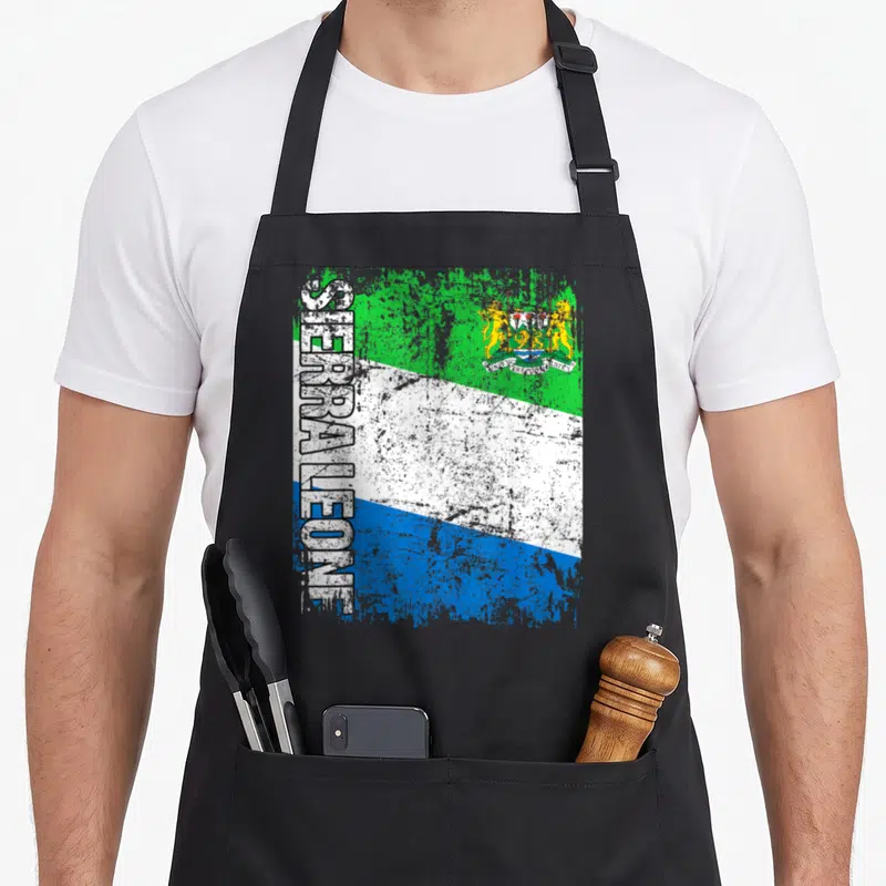 Sierra distressed apron - Vertical Sierra Leone text over green white blue distressed flag with coat of arms — shown on a black cotton canvas apron against a white background
