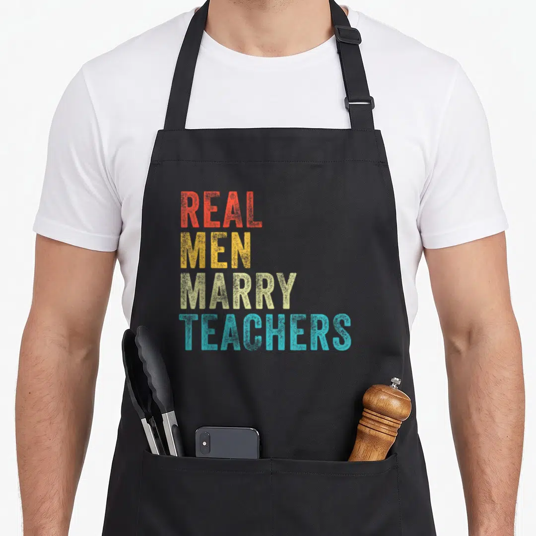 Future teacher pocket apron - Stacked text reading Real Men Marry Teachers in red yellow beige and blue block letters — shown on a black cotton canvas apron against a white background