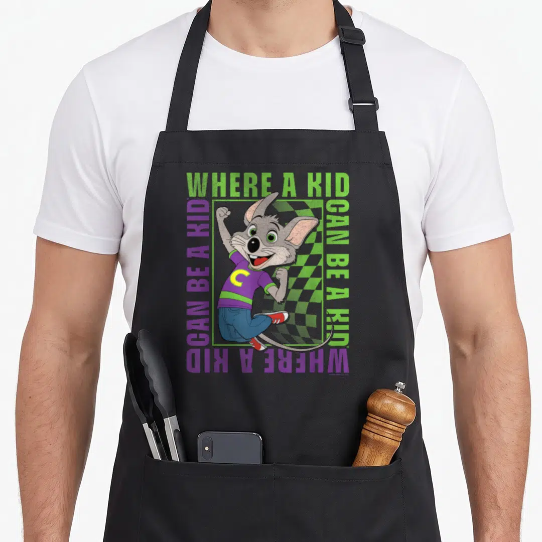 Cheese e.a apron - Grey cartoon mouse jumping inside green and purple text border reading WHERE A KID CAN BE A KID — shown on a black cotton canvas apron against a white background