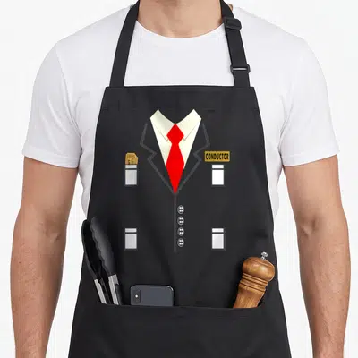Costume train conductor apron - Grey suit graphic with red tie, yellow name tag, and tickets in pocket — shown on a black cotton canvas apron against a white background