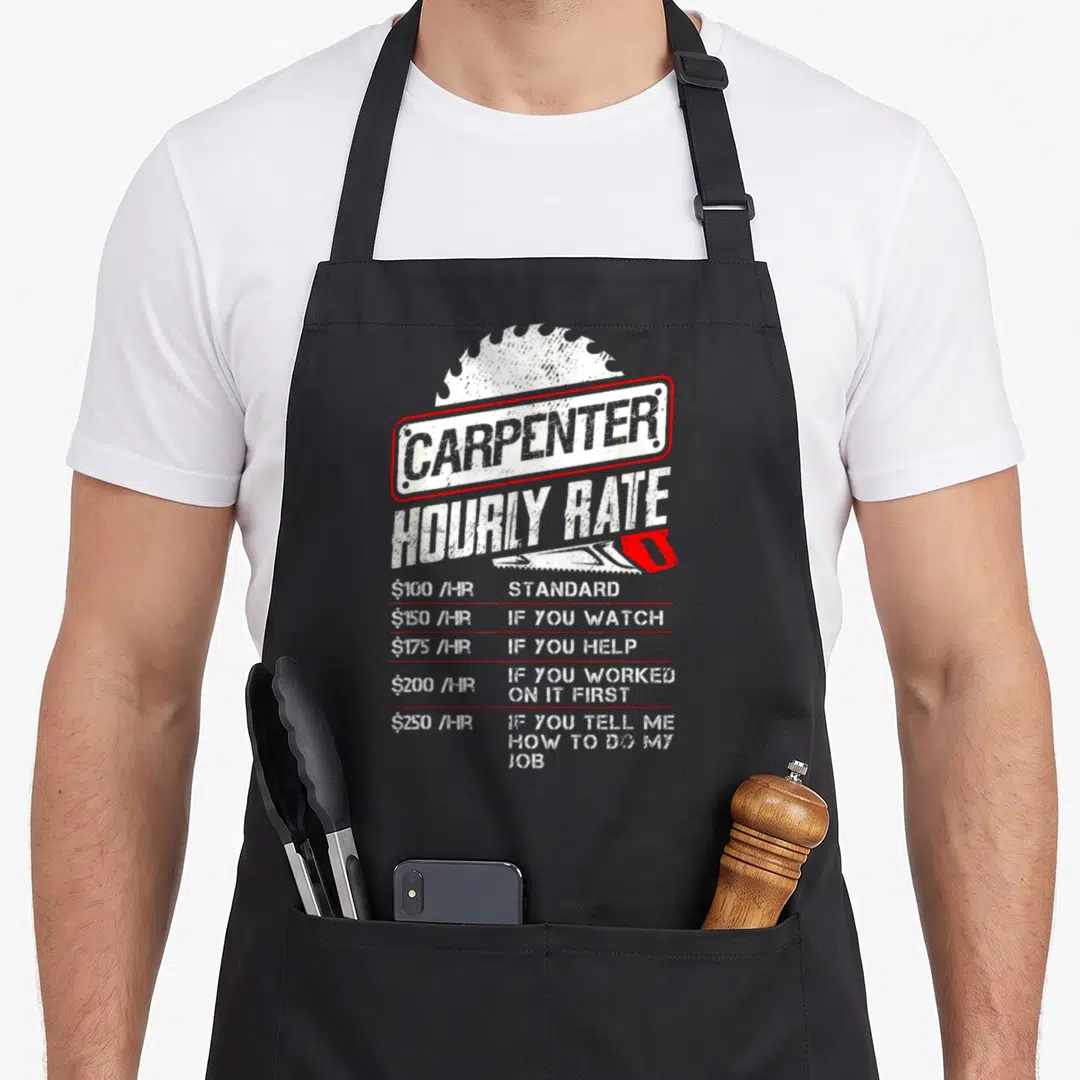 Hourly woodworking apron - Carpenter Hourly Rate text with saw blade and distressed white red typography — shown on a black cotton canvas apron against a white background