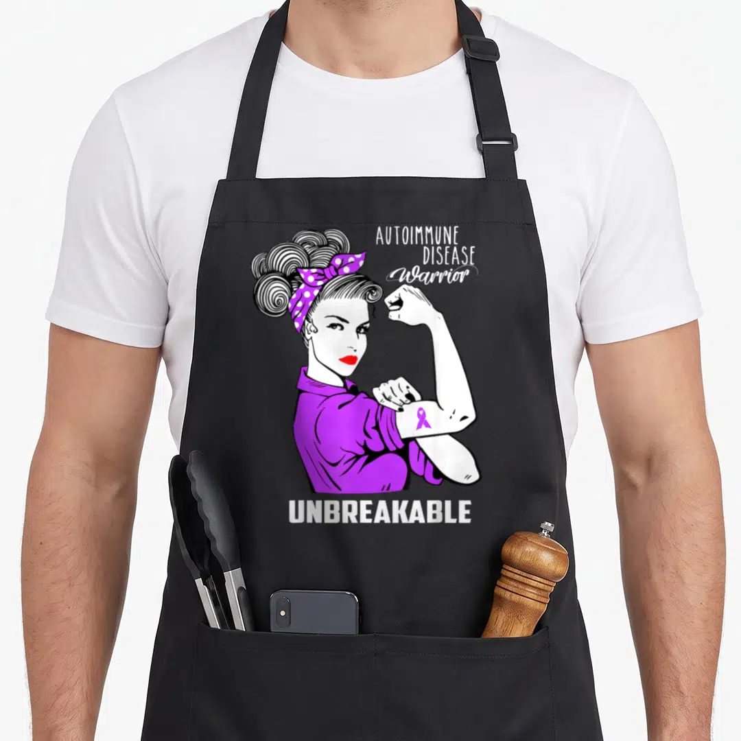 Autoimmune auto dad apron - Cartoon woman flexing arm with AUTOIMMUNE DISEASE Warrior UNBREAKABLE text and purple ribbon — shown on a black cotton canvas apron against a white background