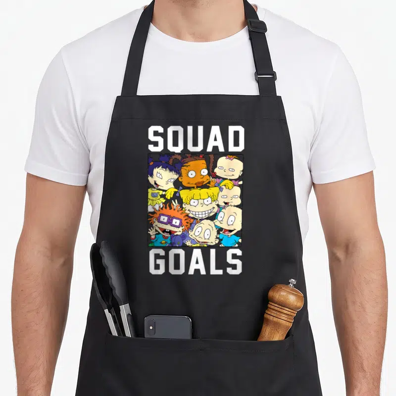 Funny goal of squad apron - Rugrats characters inside a square frame between SQUAD and GOALS text — shown on a black cotton canvas apron against a white background
