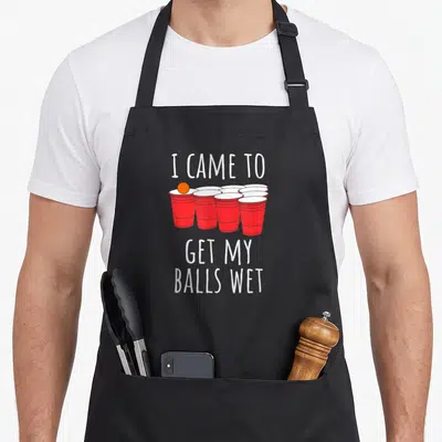 Funny beer pong apron - I came to get my balls wet text above red cups and orange ball — shown on a black cotton canvas apron against a white background
