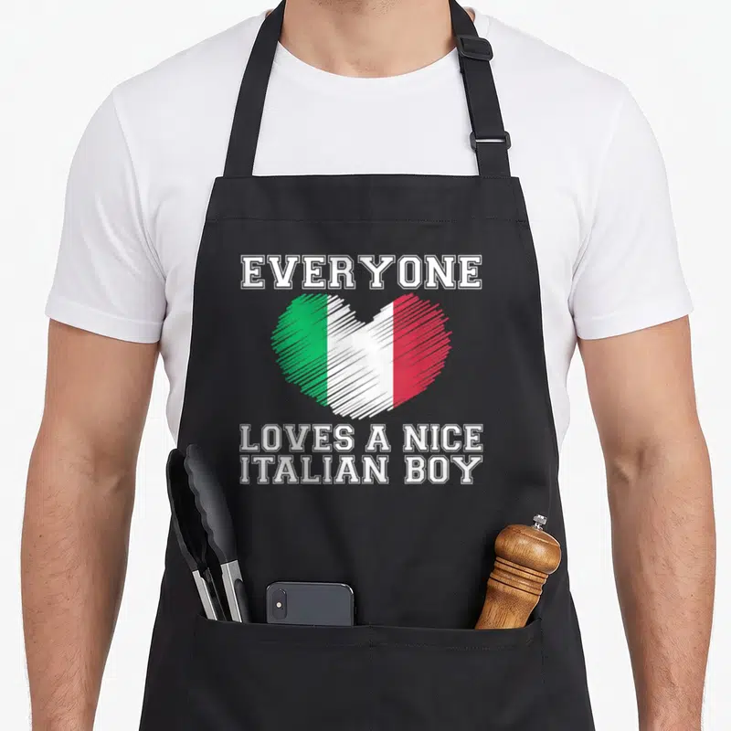 Italian flag italy apron - Heart with white green red stripes and everyone loves a nice italian boy text — shown on a black cotton canvas apron against a white background