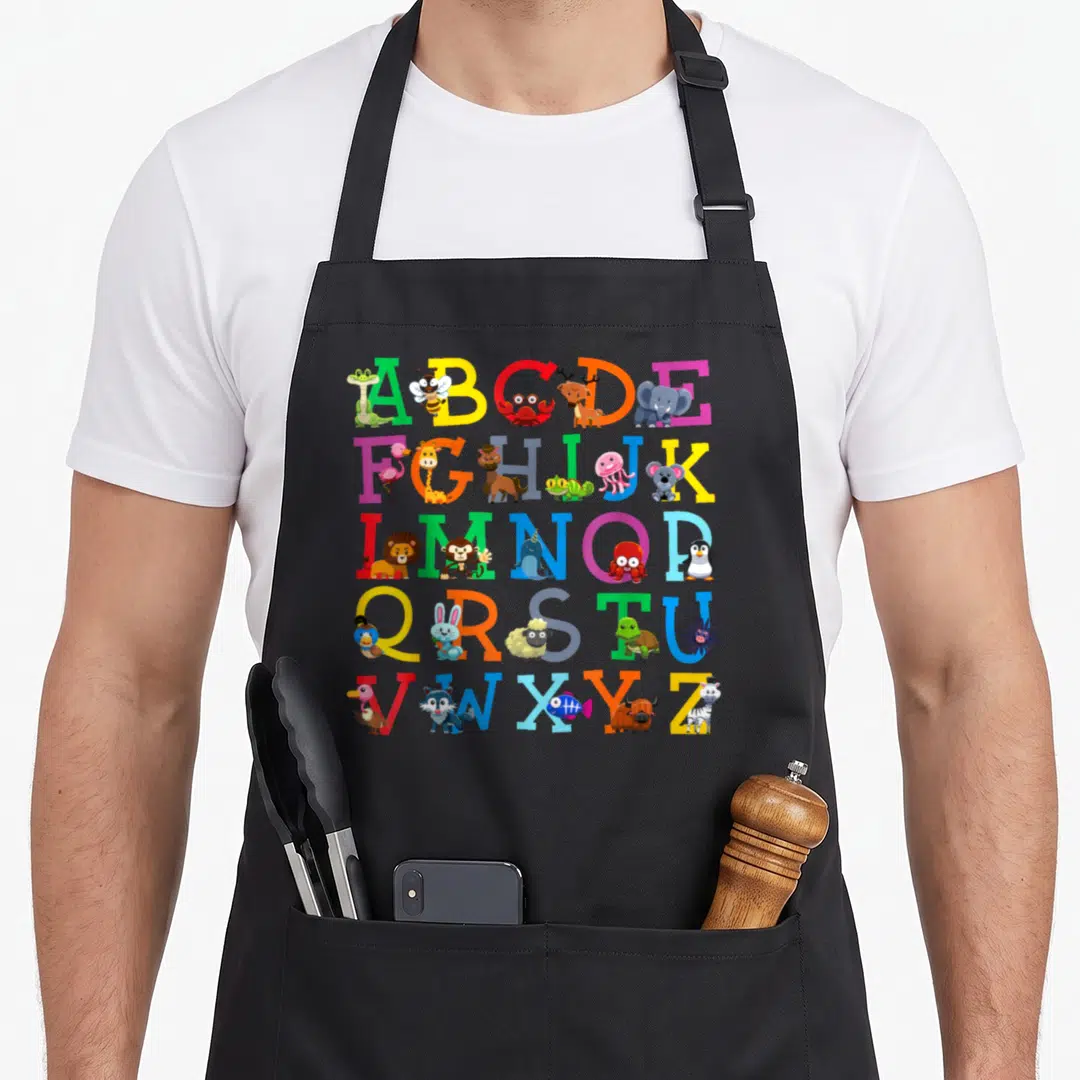 Letter animal apron - A-Z alphabet grid with cartoon bee elephant zebra in green blue red yellow pink — shown on a black cotton canvas apron against a white background