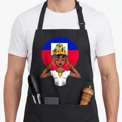 Melanin haitian queen apron - Cartoon woman with gold crown and afro in front of circular Haitian flag in blue red gold — shown on a black cotton canvas apron against a white background