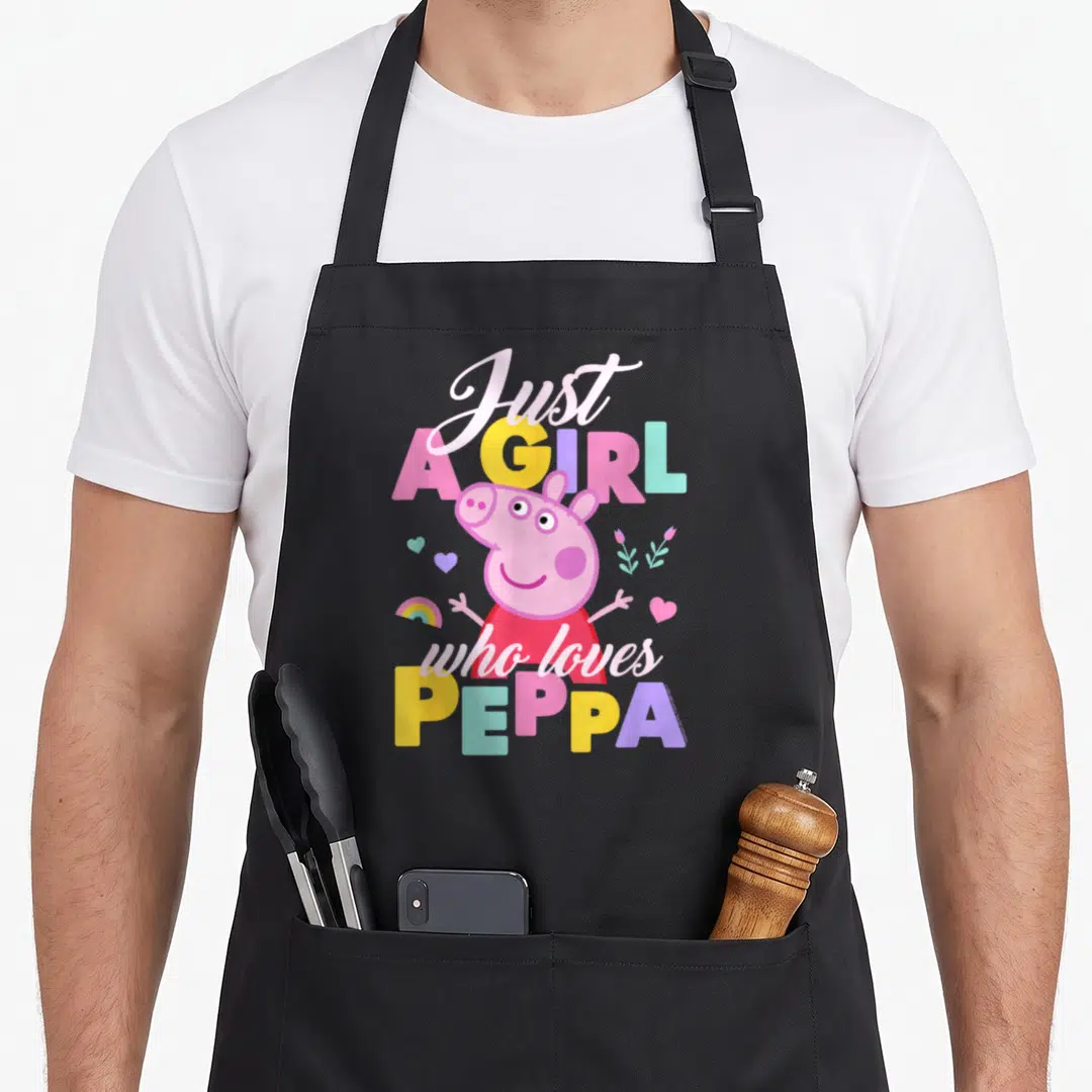 Playing pig apron - Just A GIRL who loves PEPPA cartoon text with pink character and scattered hearts flowers rainbow — shown on a black cotton canvas apron against a white background