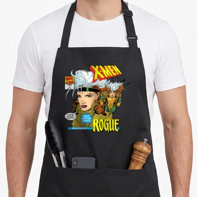 Rogue hobby apron - X-Men comic cover art with Rogue portrait, speech bubbles, and yellow blue lettering — shown on a black cotton canvas apron against a white background