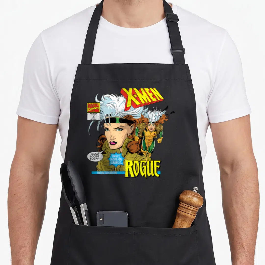 Rogue hobby apron - X-Men comic cover art with Rogue portrait, speech bubbles, and yellow blue lettering — shown on a black cotton canvas apron against a white background