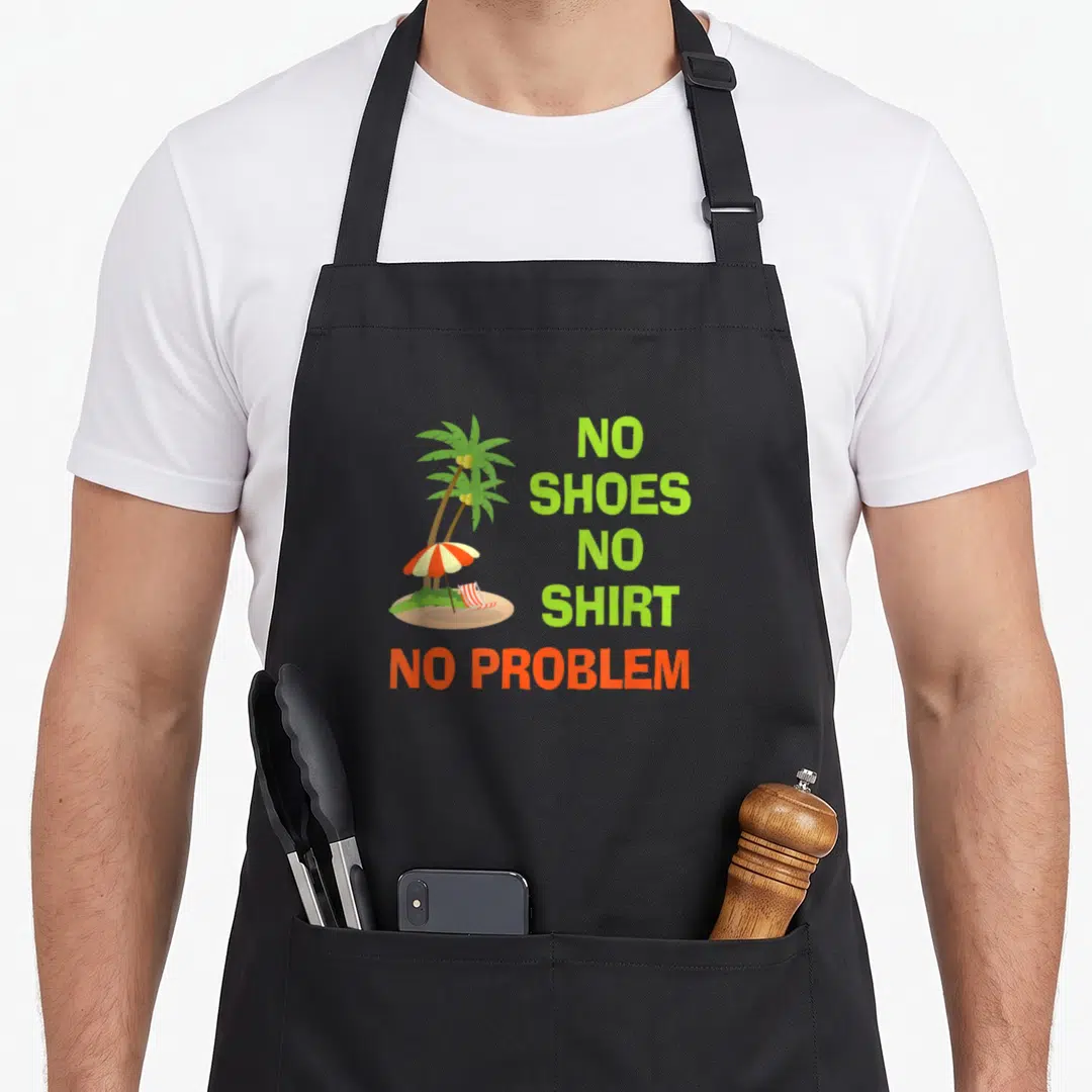 Shoe kitchen island apron - Cartoon palm tree with striped chair and stacked text NO SHOES NO SHIRT NO PROBLEM — shown on a black cotton canvas apron against a white background