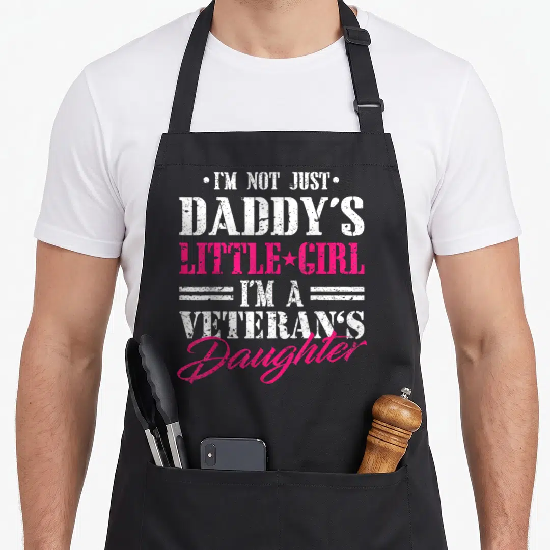 Veteran daddy apron - Distressed text reading I'm not just Daddy's little girl I'm a veteran's daughter — shown on a black cotton canvas apron against a white background