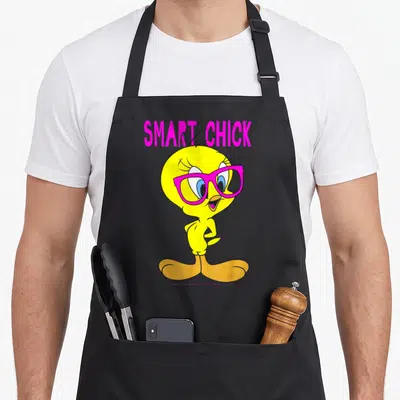 Tweety smart apron - Yellow cartoon bird wearing pink glasses under pink SMART CHICK text — shown on a black cotton canvas apron against a white background