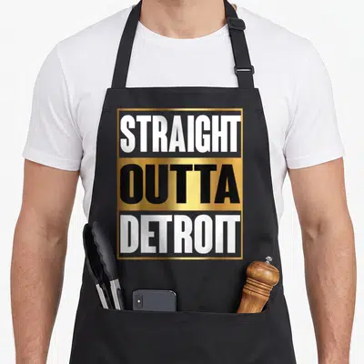 Straight detroit apron - Stacked STRAIGHT OUTTA DETROIT text in gold white and black within a border — shown on a black cotton canvas apron against a white background