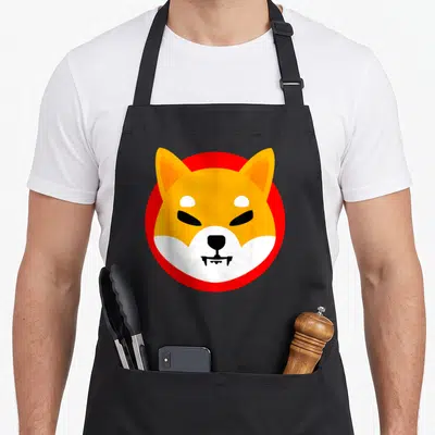 Shiba coin apron - Cartoon shiba inu head in orange and white on red circle, black bib apron — shown on a black cotton canvas apron against a white background