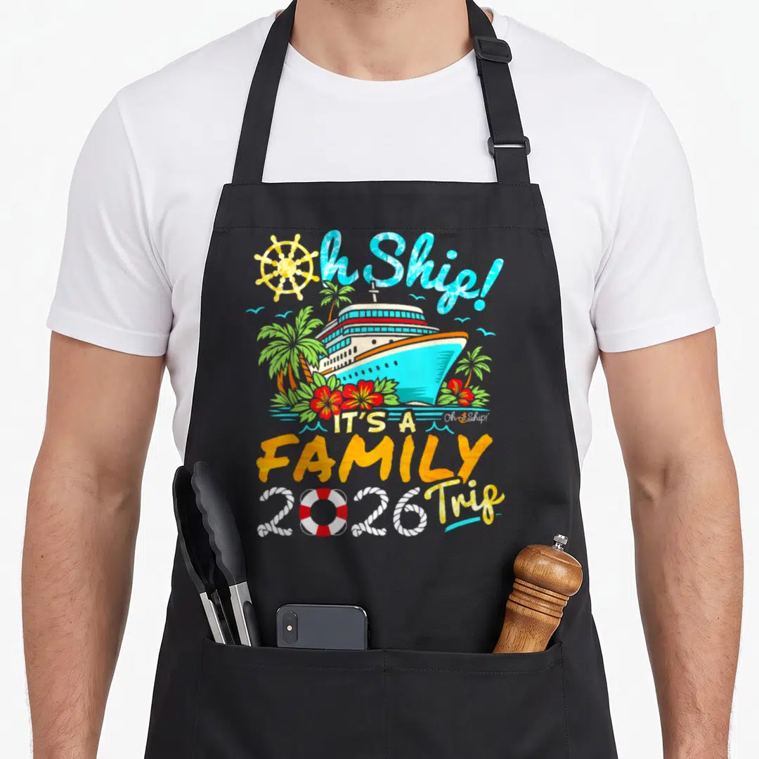 Ship family aprons - Cartoon cruise ship with palm trees and Oh Ship It's a Family Trip 2026 text — shown on a black cotton canvas apron against a white background