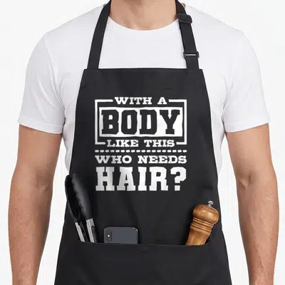 Cute body hair apron - White stacked typography reading WITH A BODY LIKE THIS WHO NEEDS HAIR with dotted line separator — shown on a black cotton canvas apron against a white background