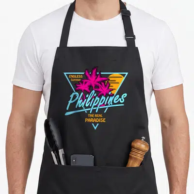 Filipino vietnamese girl apron - Retro graphic with pink palms, orange sun, and Philippines text inside a blue triangle — shown on a black cotton canvas apron against a white background