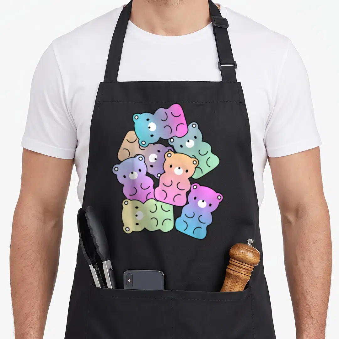 Rainbow bear apron - Seven overlapping gummy bears in pink, blue, green, yellow, and purple gradients — shown on a black cotton canvas apron against a white background