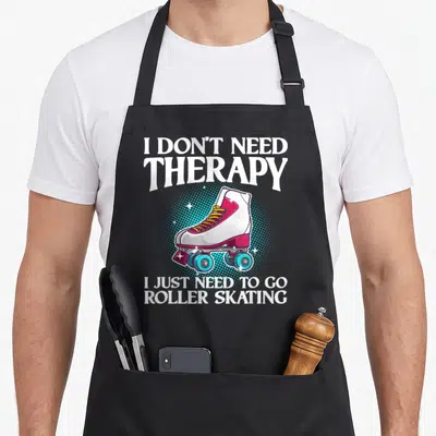 Roller inline skating apron - Cartoon quad skate in white pink blue and yellow on blue halftone circle with therapy — shown on a black cotton canvas apron against a white background