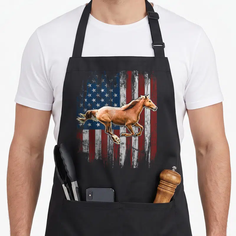 Horse american flag apron - Galloping brown horse on distressed red white and blue flag background — shown on a black cotton canvas apron against a white background