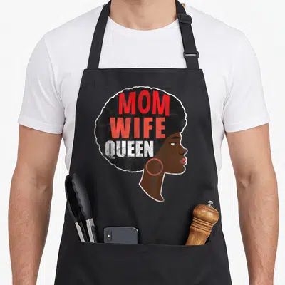 Special mother's day aprons - Cartoon woman profile with black afro containing stacked red and white text reading MOM — shown on a black cotton canvas apron against a white background
