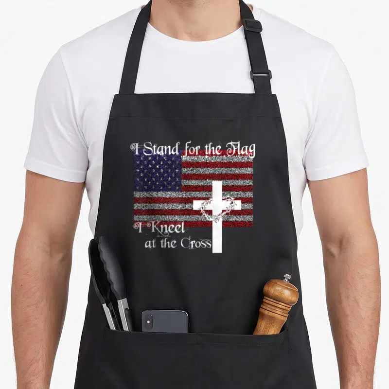 Patriotic cross apron - Distressed USA flag with white cross crown of thorns and patriotic Christian text in red white — shown on a black cotton canvas apron against a white background
