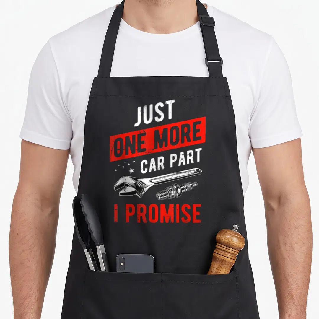 Part car apron - Just One More Car Part I Promise text with wrench and spark plug in white red black distressed style — shown on a black cotton canvas apron against a white background