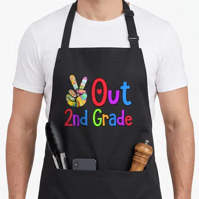 Grad 2nd apron - Multicolored peace sign next to red blue purple text Out 2nd Grade with heart — shown on a black cotton canvas apron against a white background