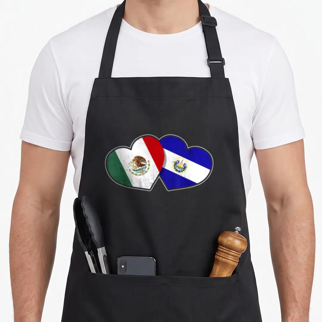 Mexican el cook apron - Two overlapping hearts filled with Mexican and Salvadorian flags in realistic green white red — shown on a black cotton canvas apron against a white background