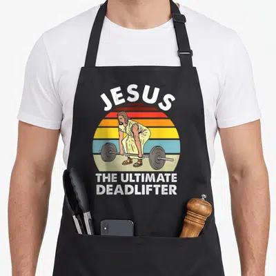 Gym ultimate apron - Retro Jesus deadlifter graphic with striped sun and white text — shown on a black cotton canvas apron against a white background