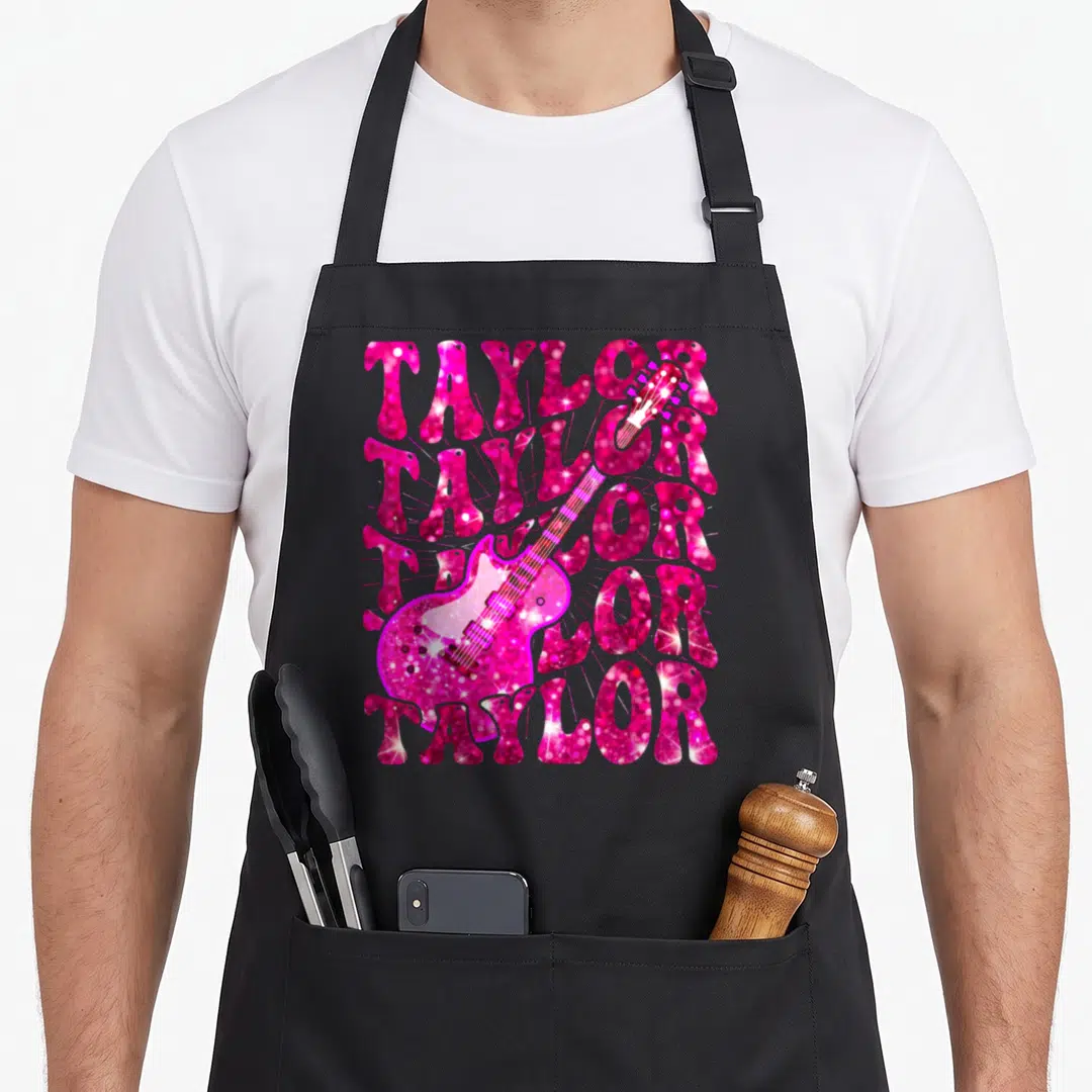 Vintage taylor 80s apron - Pink glitter electric guitar overlaid on five stacked rows of TAYLOR text — shown on a black cotton canvas apron against a white background