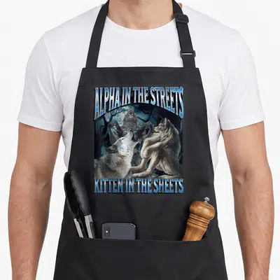 Street meme apron - Alpha in the streets kitten in the sheets werewolf howling in forest with blue text — shown on a black cotton canvas apron against a white background